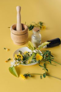 Traditional herbal medicine and acupuncture tools on yellow background.
