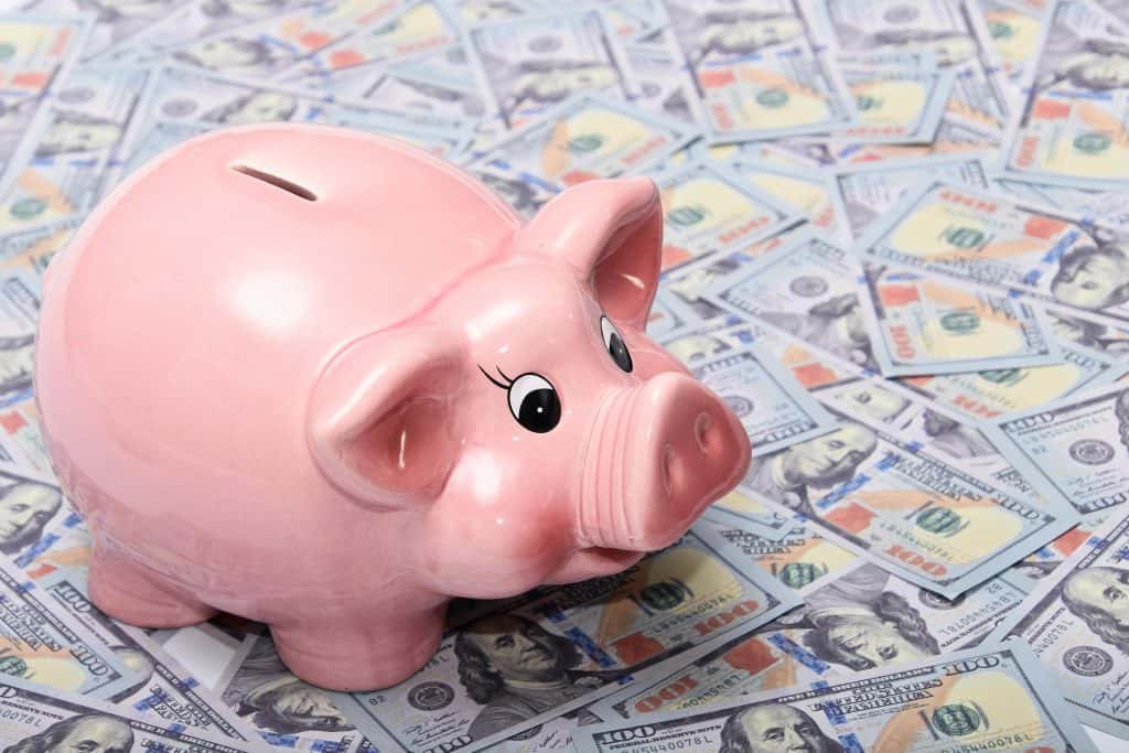 Pink piggy bank on US dollar bills representing healthcare marketing expenses.