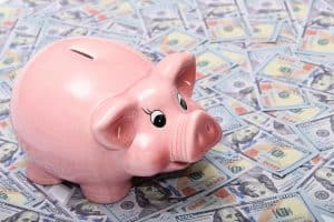 Pink piggy bank on US dollar bills representing healthcare marketing expenses.