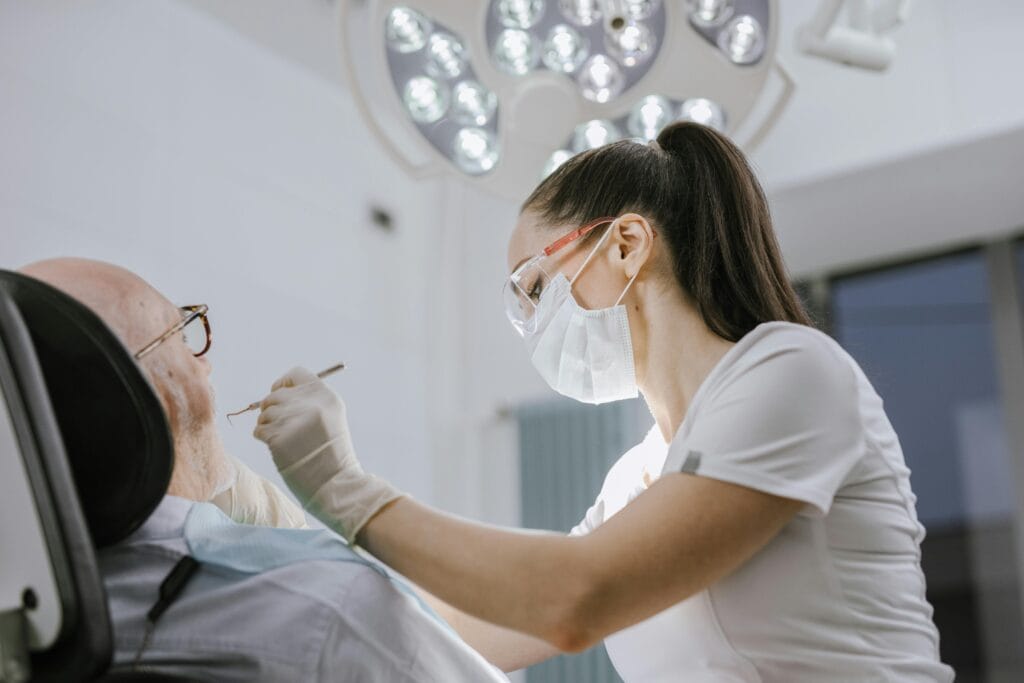 Dental professional performing oral examination on elderly patient in clinic.