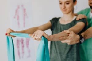 Therapist guiding a patient through resistance band shoulder exercises in a clinic