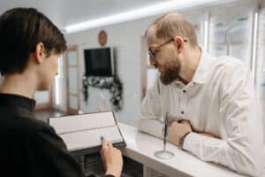 Clinic receptionist showing a patient the appointment calendar at the front desk